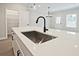 Close up of kitchen island with a stainless steel sink, white countertops, and ample storage space at 175 Bluffington Way, Marietta, GA 30066