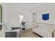 Bedroom with twin crib, gray glider, white bookcase and view into the hallway at 1325 Richland Creek Ct, Buford, GA 30518