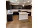 Modern kitchen with dark cabinets, granite countertops, stainless steel appliances, and hardwood floors at 4375 Easter Lily Ave Lot 81, Buford, GA 30519