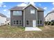 View of the back of a two-story gray home with a small patio and grassy yard at 2466 Bear Mountain St, Lithonia, GA 30058