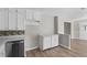 Bright kitchen area with white cabinets, a stainless steel dishwasher, and durable wood-look flooring at 7323 Howard Pl, Jonesboro, GA 30236