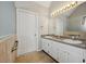 Bathroom with double sinks, white cabinetry, and a large mirror providing ample vanity space at 1128 Strath Clyde Way, Mcdonough, GA 30253