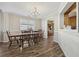 Dining room with classic chandelier, large window, and an open view into the kitchen, featuring laminate flooring at 1128 Strath Clyde Way, Mcdonough, GA 30253