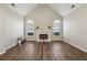 Spacious living room with vaulted ceilings, a decorative fireplace, large arched windows, and laminate flooring at 1128 Strath Clyde Way, Mcdonough, GA 30253