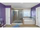 Well-lit primary bathroom with shower and soaking tub has purple accent wall at 205 Bergen Dr, Fayetteville, GA 30215