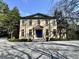 Elegant stone home with a blue front door, manicured landscaping and a circular drive at 973 Peachtree Battle Ave, Atlanta, GA 30327