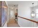 Well-lit hallway with a decorative light fixture, wood railing, and neutral walls at 3641 Devenwood Way, Buford, GA 30519