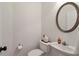 Small powder room with round mirror and sink and a dark door knob at 3641 Devenwood Way, Buford, GA 30519