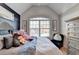 Bedroom featuring a large window with blinds and a bed with a gray velvet headboard and blue bedding at 2640 Paddock Point Pl, Dacula, GA 30019