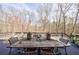 Outdoor deck with dining table overlooking a wooded area and decorative string lights at 350 Newcastle Dr, Alpharetta, GA 30009