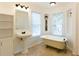 Bright bathroom with a vintage-style clawfoot tub, pedestal sink, and built-in shelving at 1316 Milstead Ave, Conyers, GA 30012