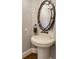 Stylish powder room with a pedestal sink, ornate mirror, and hardwood floors at 4820 Marina Ln, Mableton, GA 30126