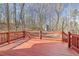 Exterior deck area with a painted red wooden railing and floor, surrounded by trees in a natural setting at 2070 Sweetgum Trl, Cumming, GA 30041