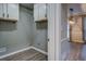 Well-lit laundry room adjacent to a living area with hardwood floors and gray walls at 2070 Sweetgum Trl, Cumming, GA 30041