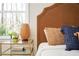 Close-up on a bedroom side table with lamp, decor, and a headboard upholstered with brown fabric at 2722 Glenbriar Ne Dr, Atlanta, GA 30345