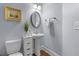 Stylish powder room with pedestal sink, decorative mirror, modern light fixture, and hardwood floors at 7630 Glisten Ave # 304, Atlanta, GA 30328