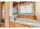 Bathroom featuring a large tub with tile surround and a picture window at 2046 Woodside Park Dr, Woodstock, GA 30188