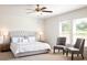 Bright bedroom featuring a tufted headboard, ceiling fan, and two chairs near the window at 45 Champions Blvd, Dallas, GA 30157