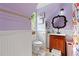 A bathroom with a wooden vanity, toilet, and floral shower curtain next to wainscoting halfway up the wall at 6510 Akins Way, Cumming, GA 30041
