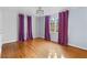 Sunlit bedroom featuring hardwood floors, a modern ceiling fan, and large windows with stylish purple and white curtains at 1824 Windemere Ne Dr, Atlanta, GA 30324