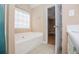 A large soaking tub sits below a window in this light-filled bathroom at 104 Providence Dr, Carrollton, GA 30116