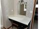 Bathroom vanity with a light fixture, mirror, neutral patterned wallpaper, and a tan upholstered stool at 92 Indian Lake Ct, Hiram, GA 30141