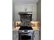 Close-up of a gas oven range with decorative tile backsplash and overhead vent at 92 Indian Lake Ct, Hiram, GA 30141