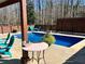 Backyard pool with chairs, table, and privacy fence, set amongst mature trees on a sunny day at 92 Indian Lake Ct, Hiram, GA 30141