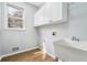 Functional laundry room with hardwood floors, storage cabinets, and a utility sink at 385 Sweet Ivy Ln, Lawrenceville, GA 30043