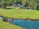 A stunning view of a modern home with a pond and flowing creek, set amidst a sprawling green lawn and lush trees at 441 Pumpkinvine Rd, Acworth, GA 30101