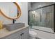 Stylish bathroom featuring a stone vessel sink, circular wood-framed mirror, and a shower-tub combo with glass doors at 441 Pumpkinvine Rd, Acworth, GA 30101