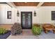 Elegant front door with decorative lanterns, brick accents, manicured landscaping and a wooden bench at 441 Pumpkinvine Rd, Acworth, GA 30101
