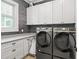 Modern laundry room features gray cabinetry, a window, and front load washer and dryer at 441 Pumpkinvine Rd, Acworth, GA 30101