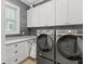 Modern laundry room features gray cabinetry, a window, and front load washer and dryer at 441 Pumpkinvine Rd, Acworth, GA 30101