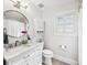 Bright bathroom featuring a vanity with a marble countertop, round mirror, and white tiled floors at 3776 Powers Ferry Nw Rd, Atlanta, GA 30342