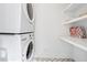 Convenient utility room with stacked washer and dryer and shelving offers functionality and storage space at 3776 Powers Ferry Nw Rd, Atlanta, GA 30342