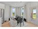 Bright breakfast nook features many windows, black table and modern furniture at 424 Hatcher Ct, Hampton, GA 30228