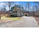 Exterior side view of a tan home with a long driveway, three car garage, and a separate storage shed at 3850 Pilgrim Mill Rd, Cumming, GA 30041