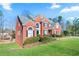 A charming side view of a two-story red brick home with a well-manicured lawn at 325 Stonecastle Pass, South Fulton, GA 30331