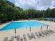 Large community pool surrounded by lounge chairs and umbrellas with mature trees at 325 Stonecastle Pass, South Fulton, GA 30331