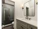 Modern bathroom with a glass-door shower, gray vanity, and a sleek, black-framed mirror at 11572 Serenbe Ln, Chattahoochee Hills, GA 30268