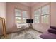 Light pink bedroom featuring three windows, a desk, chair, daybed, and stylish rug at 11572 Serenbe Ln, Chattahoochee Hills, GA 30268