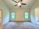 Spacious bedroom with a ceiling fan, neutral carpet, and windows overlooking a green landscape at 121 Honey Creek Rd, Conyers, GA 30094