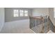 Open loft area with carpet, large windows, and a staircase with an iron railing at 400 Hatcher Ct, Hampton, GA 30228