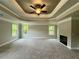 Spacious main bedroom featuring a tray ceiling, ceiling fan, carpeted floors and modern fireplace at 123 Honey Creek Rd, Conyers, GA 30094