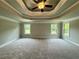 Spacious main bedroom featuring a tray ceiling, ceiling fan and carpeted floors with plenty of natural light at 123 Honey Creek Rd, Conyers, GA 30094