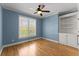 Light-filled bedroom with hardwood floors, blue walls, ceiling fan, and built-in shelving at 3070 Corsair Curv, Cumming, GA 30040