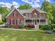 Charming two-story brick home featuring a cozy front porch and manicured lawn at 3070 Corsair Curv, Cumming, GA 30040
