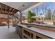 Covered outdoor kitchen with bar seating and outdoor sink overlooks inground pool in backyard at 3070 Corsair Curv, Cumming, GA 30040