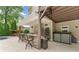 The outdoor kitchen offers a stone bar with seating, grill, and a view of the lush backyard at 3070 Corsair Curv, Cumming, GA 30040